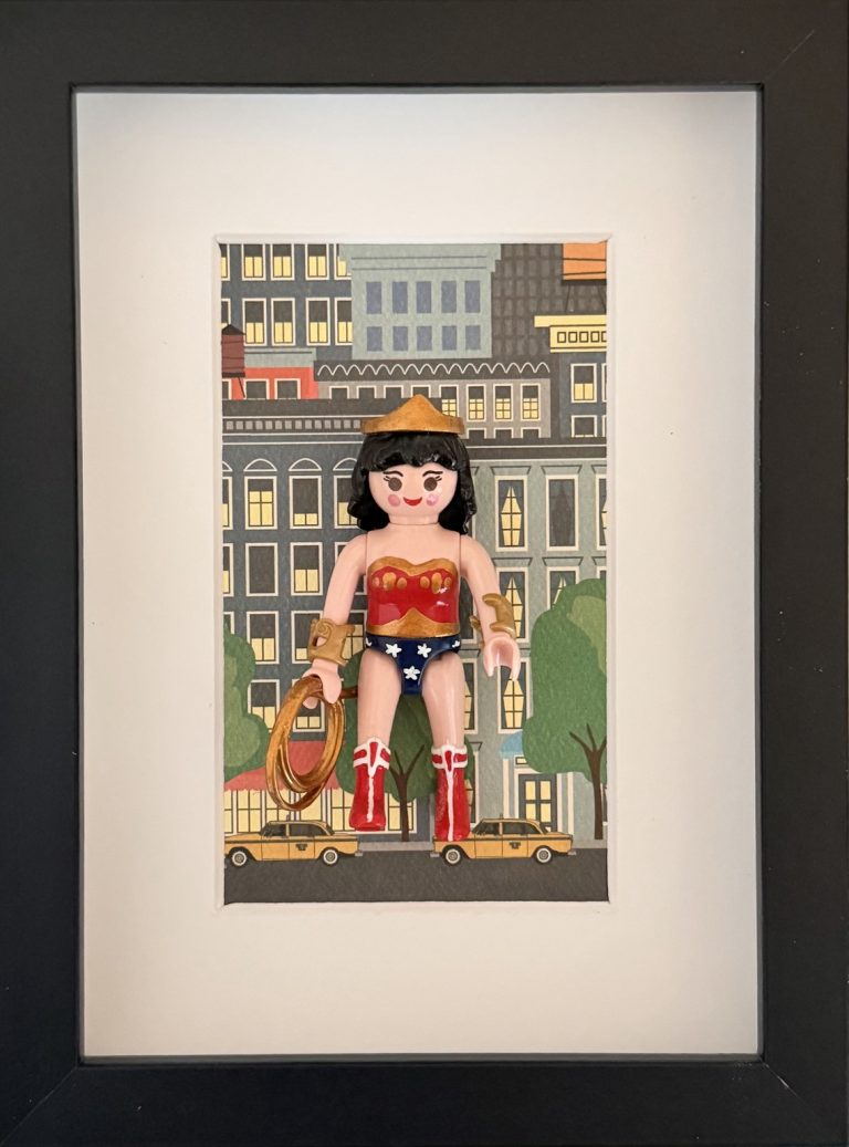 Tableau Wonder Woman avec costume rouge et bleu étoilé, lasso doré et décor urbain, dans un cadre noir à passe-partout clair.